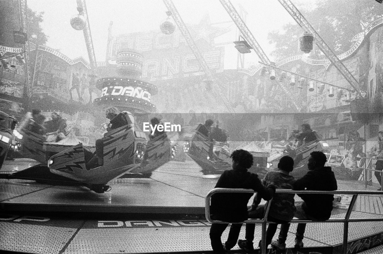 Fair with attractions and rides. a group of young people is sitting on a bench. fun and speed.