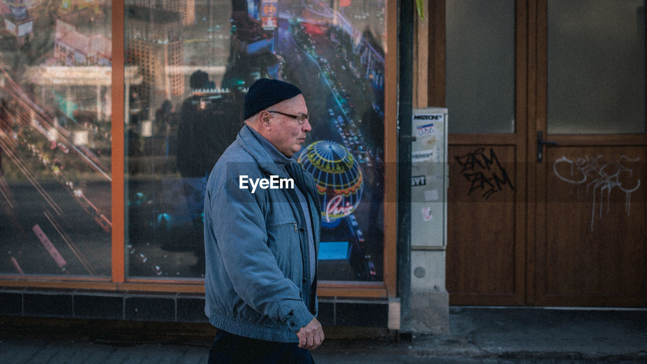 MAN STANDING BY WINDOW IN SNOW