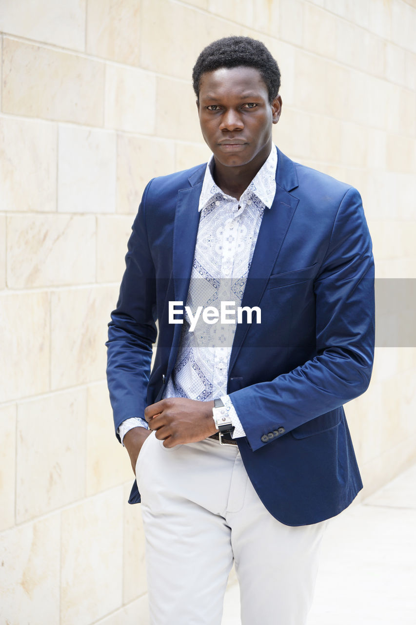 Portrait of confident businessman walking against wall