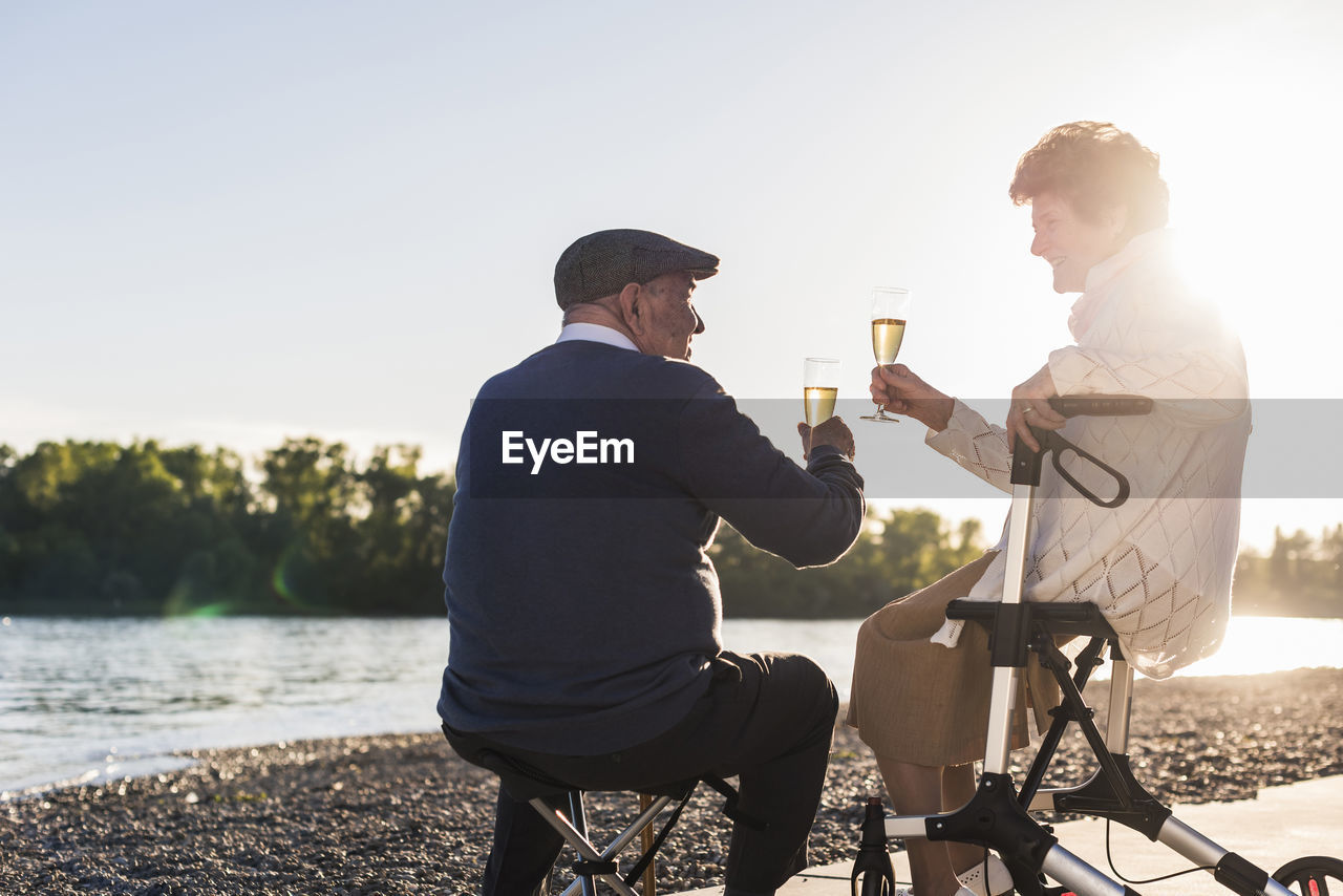 Senior couple toasting with sparkling wine at sunset