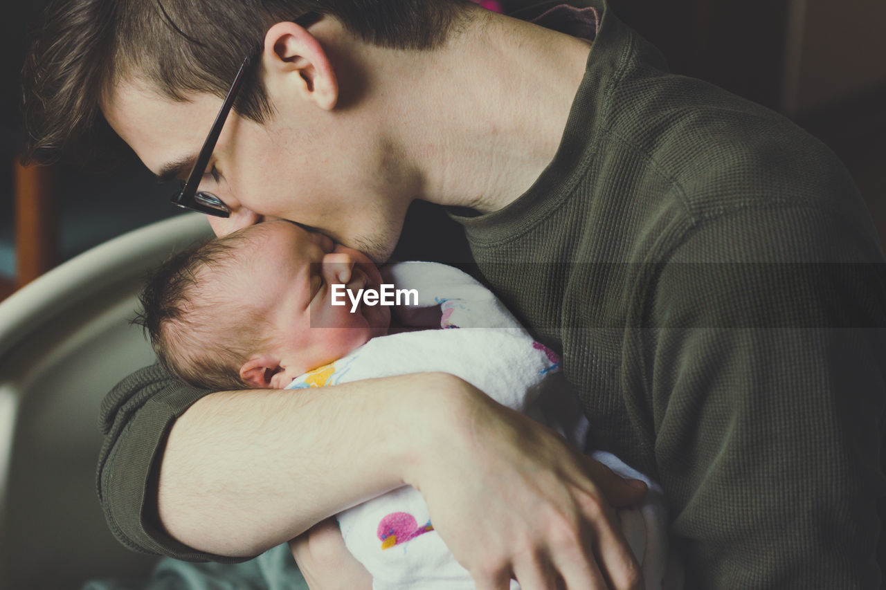 Close-up of man kissing newborn baby