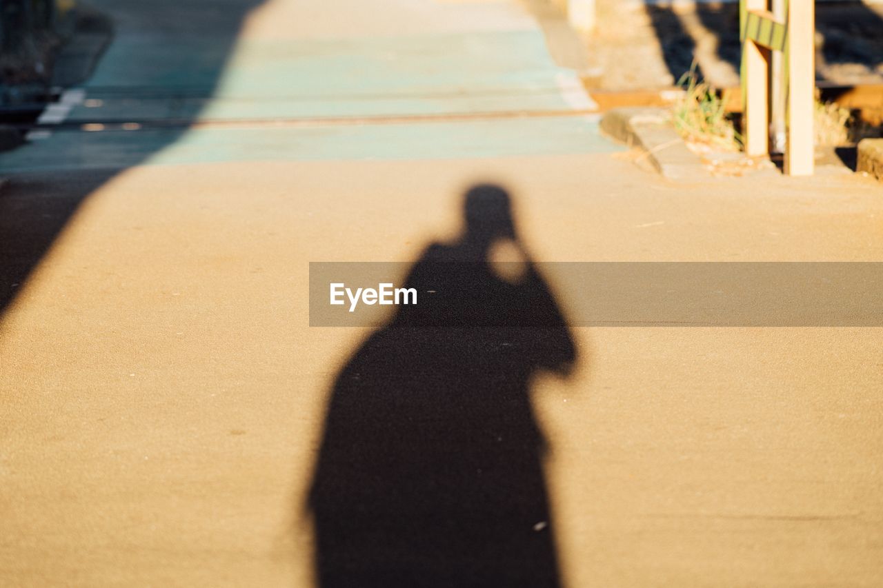 Shadow of person on footpath during sunny day