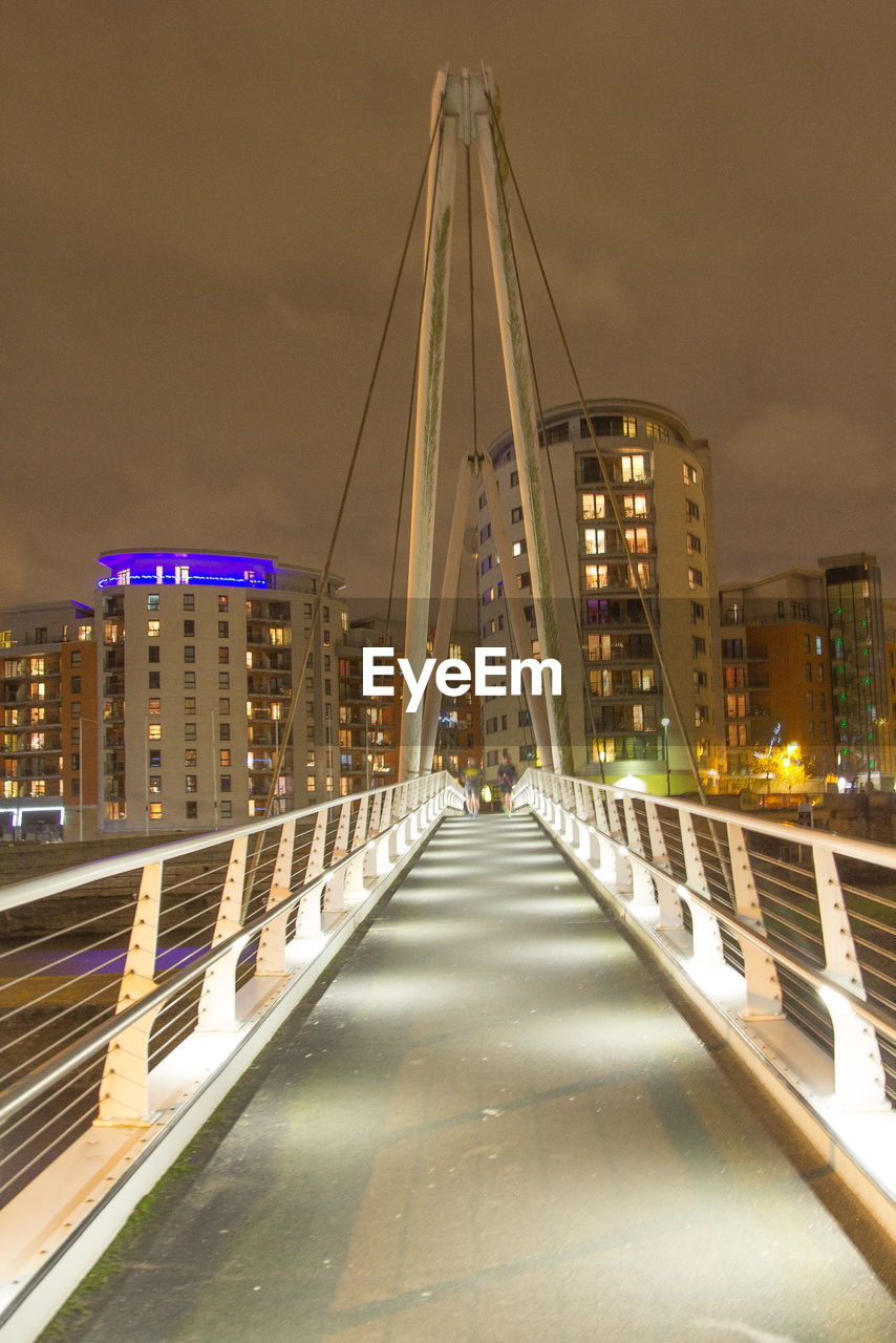 ILLUMINATED BRIDGE OVER RIVER AT NIGHT