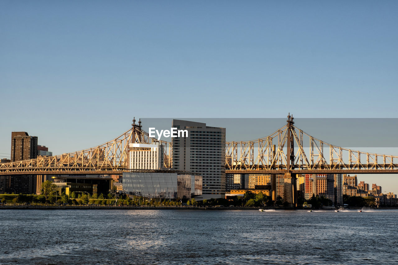 BRIDGE OVER RIVER BY BUILDINGS AGAINST SKY