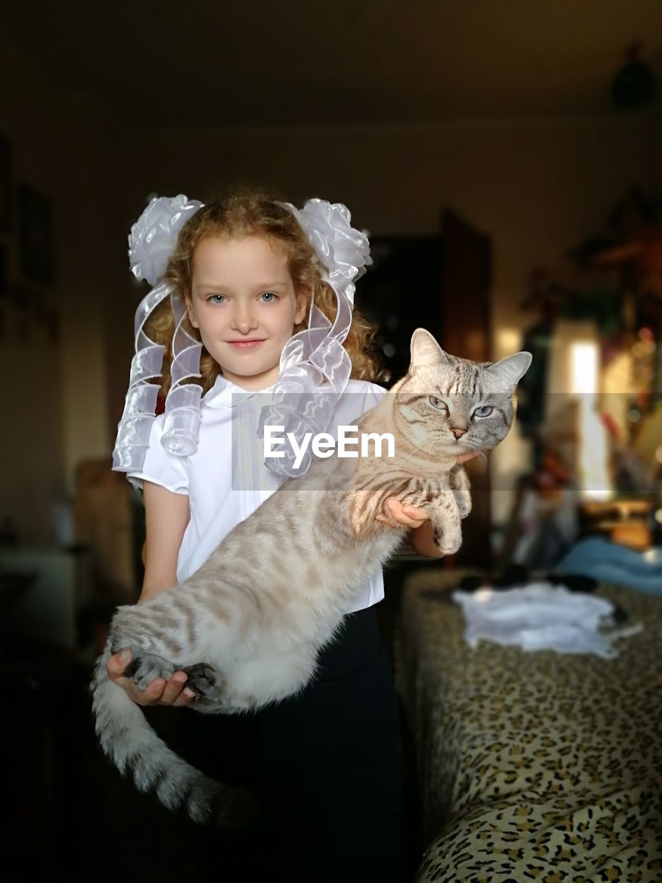 Portrait of cute girl carrying cat at home