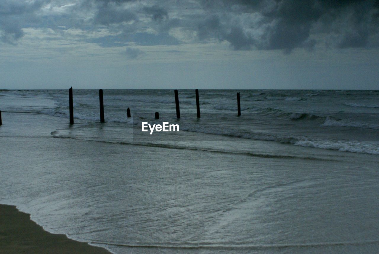 VIEW OF BEACH AGAINST CLOUDY SKY