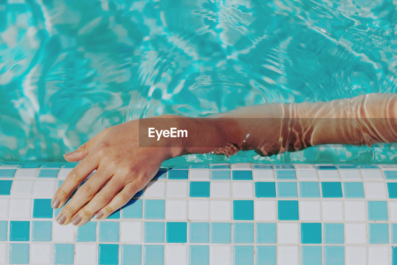 Low section of person lying on swimming pool