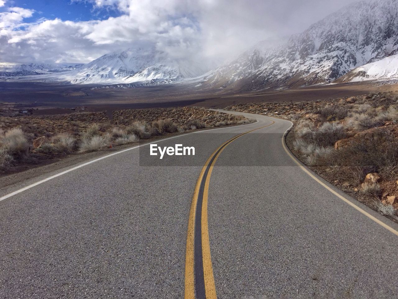 Road passing through landscape against cloudy sky