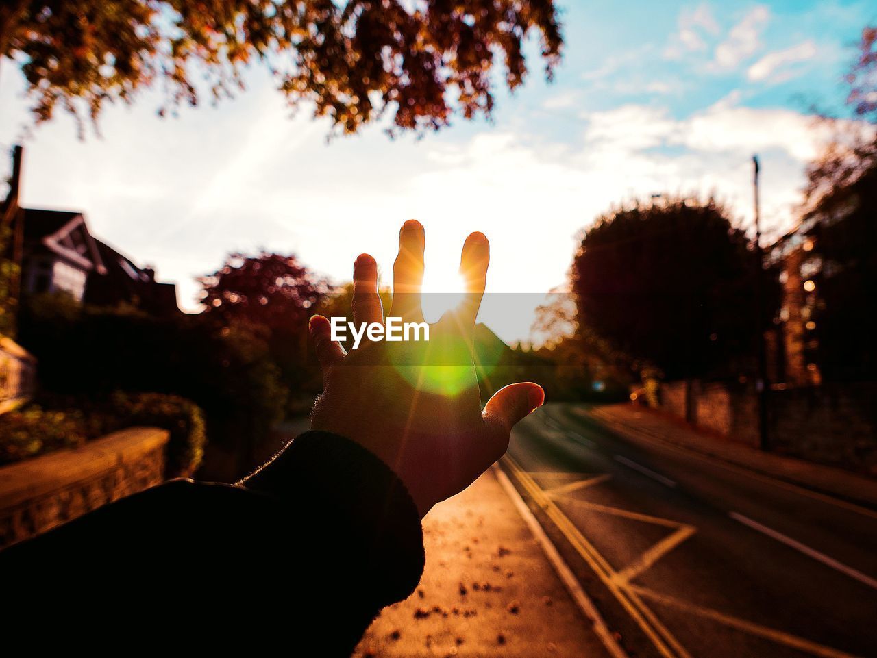 Cropped image of hand against sky during sunset