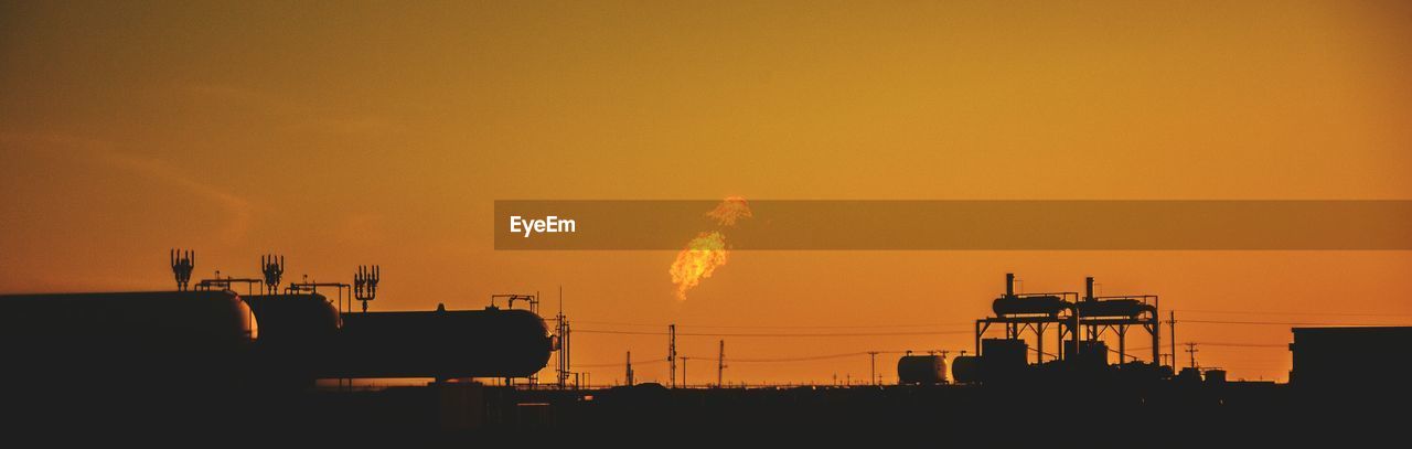 Silhouette smoke emitting from factory against sky during sunset