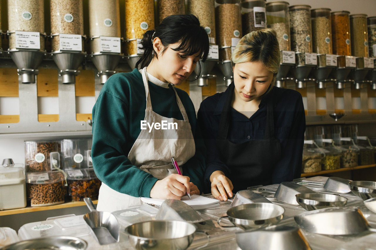 Multiracial female colleagues taking inventory in food store