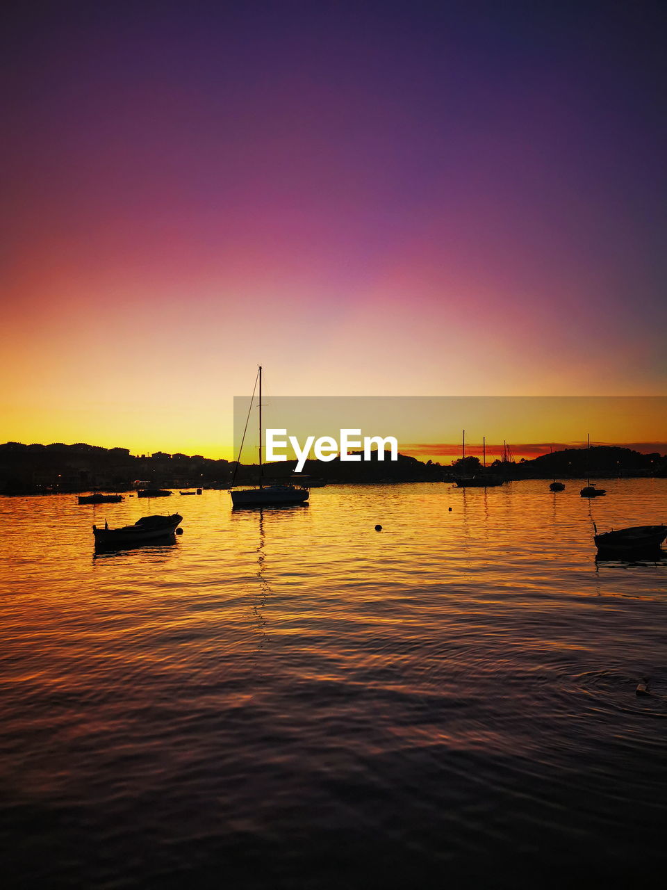 Sailboats in sea against clear sky during sunset