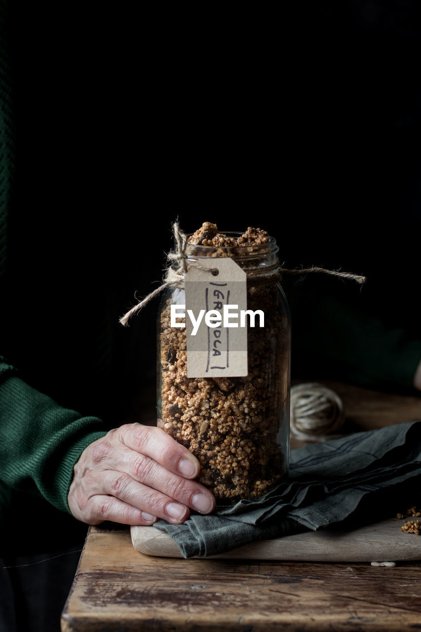 Crop woman with jar of granola