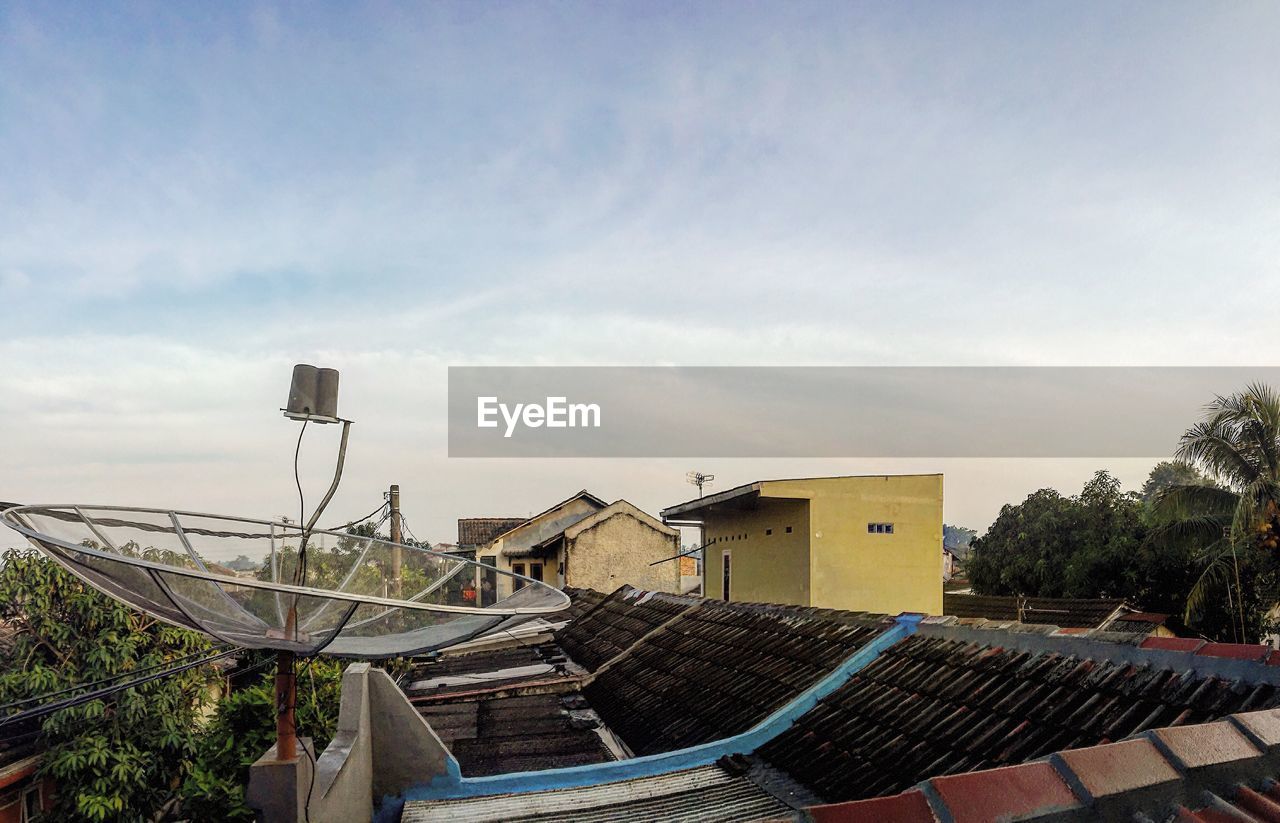 Satellite dish on house roof against sky