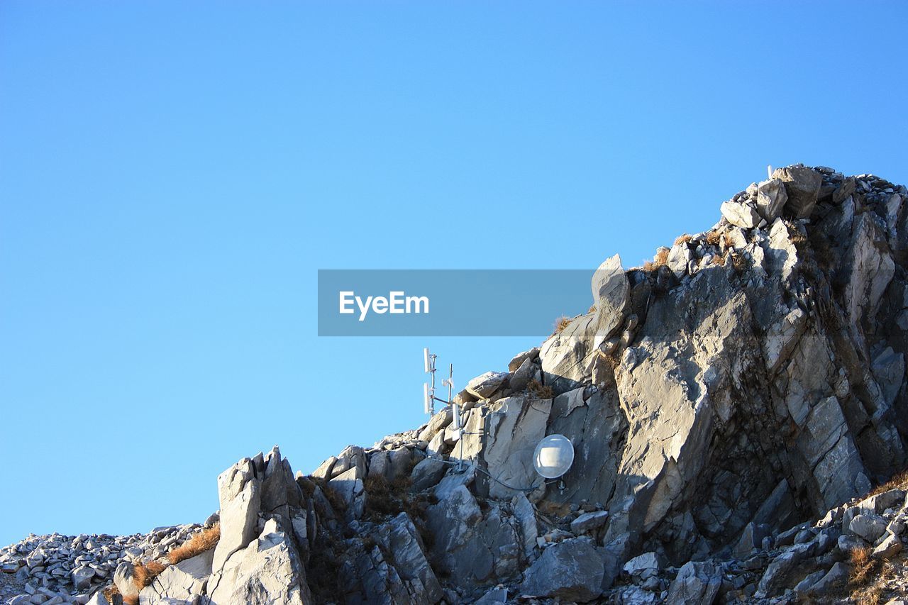 LOW ANGLE VIEW OF ROCKS AGAINST CLEAR BLUE SKY