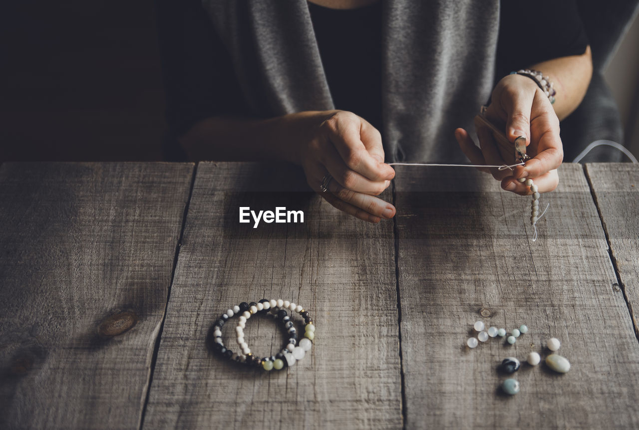 High angle view of woman making bracelets at table