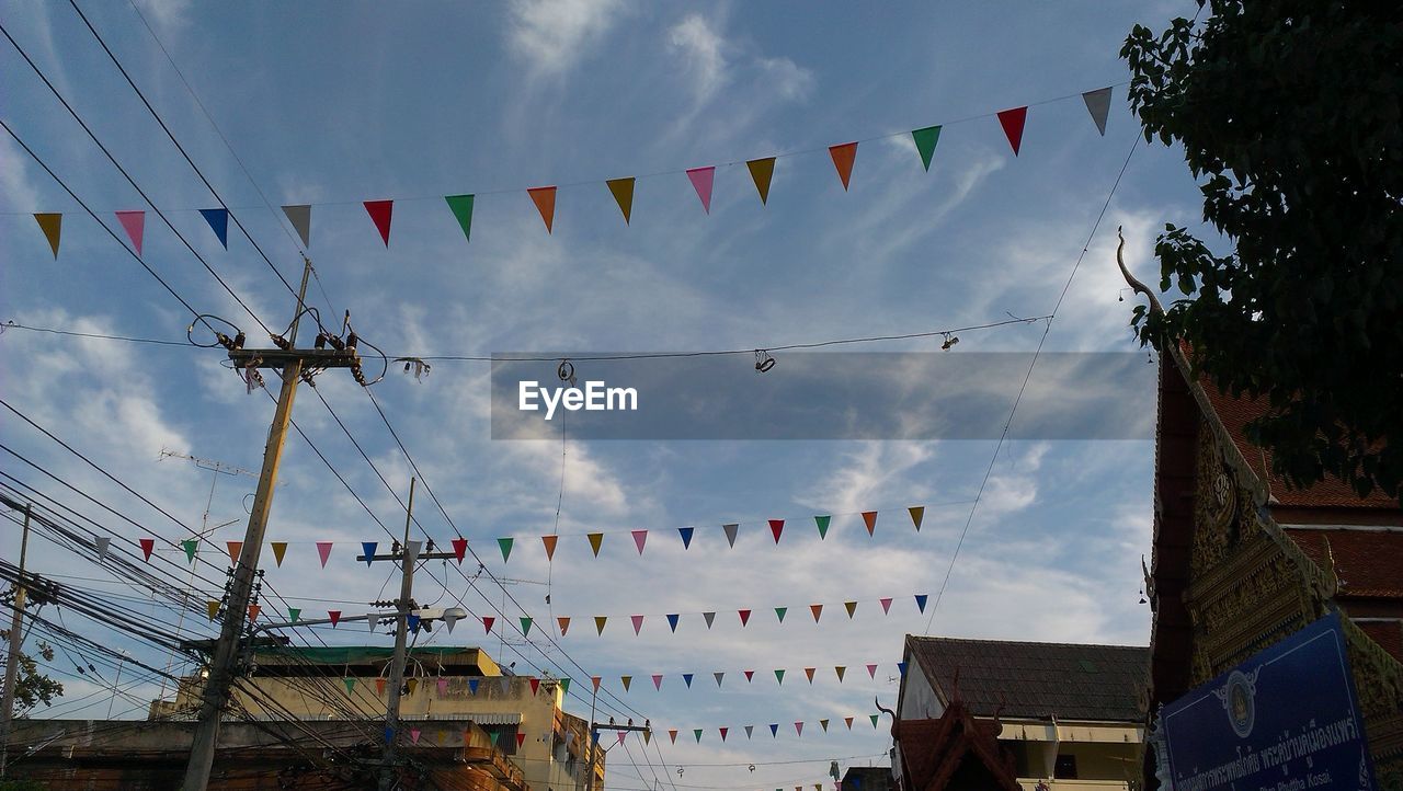 LOW ANGLE VIEW OF FLAGS HANGING AGAINST CLOUDY SKY