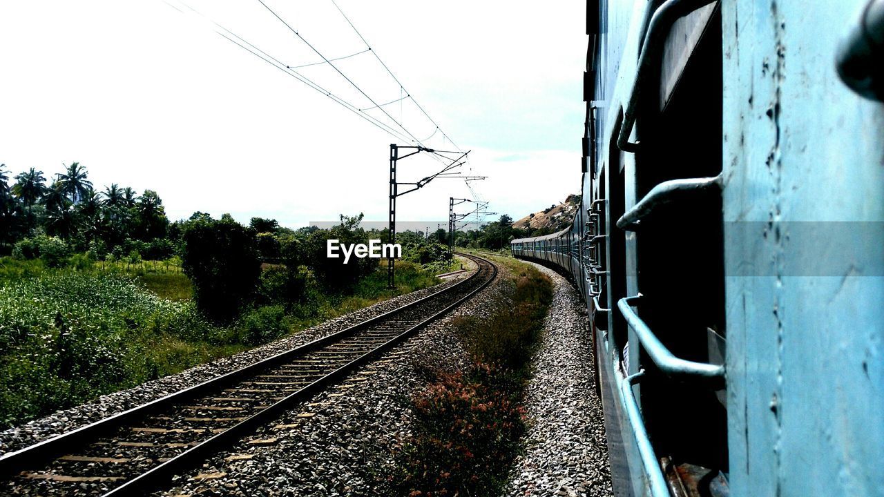 Passenger train by railroad tracks against sky