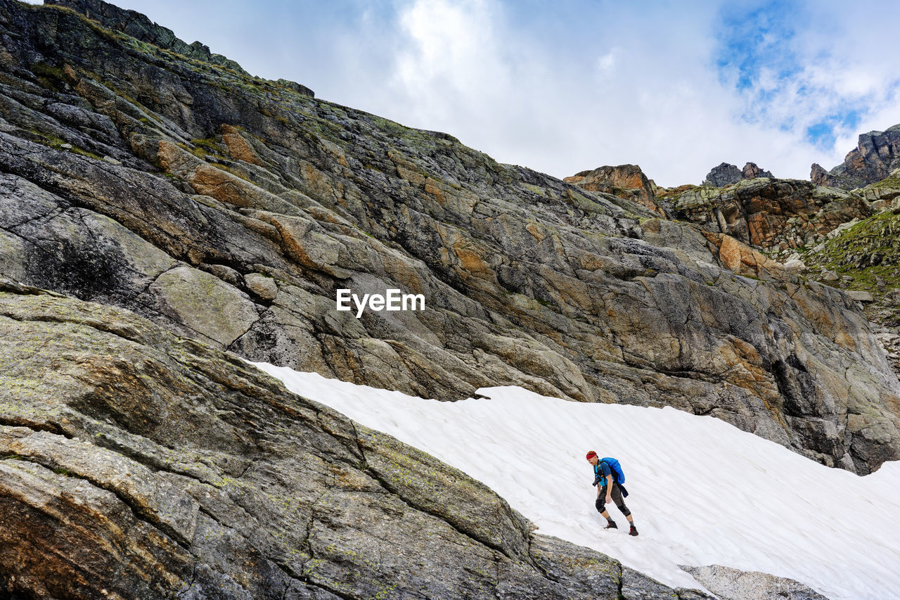 People on rocks by mountain against sky