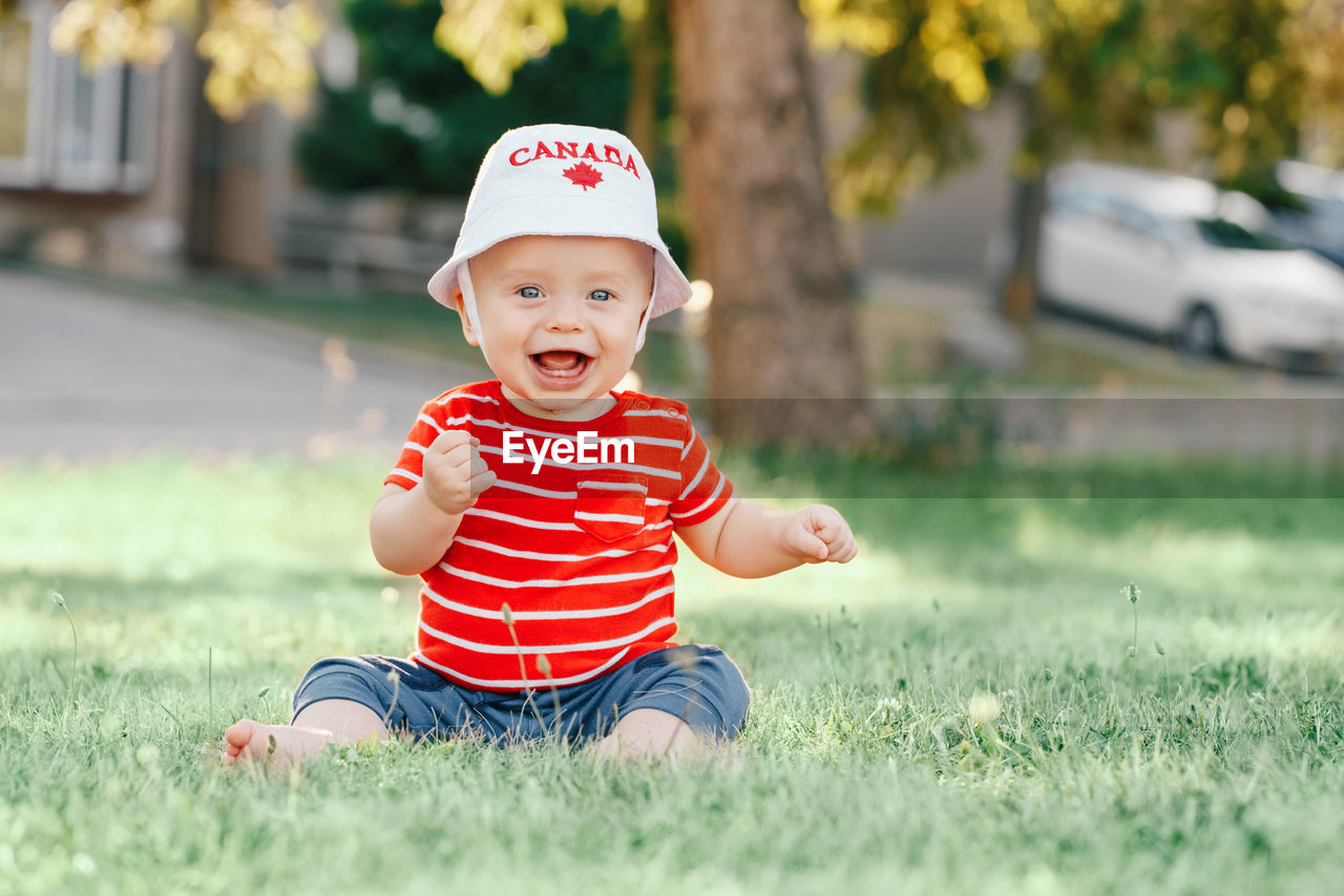 Portrait of cute baby boy sitting on grass