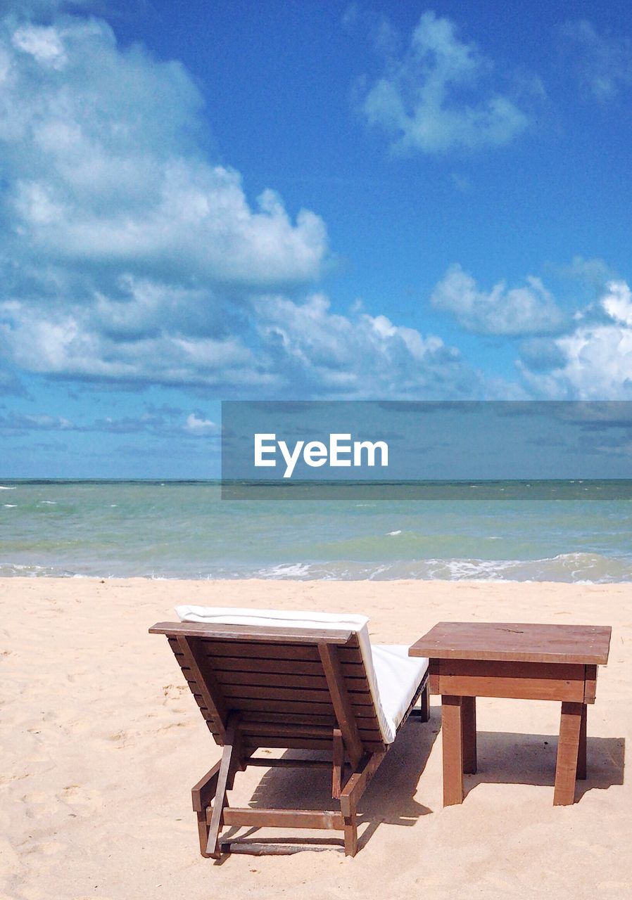 Chair on beach against sky