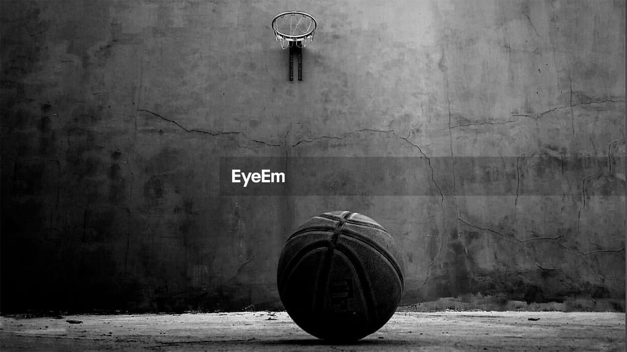 Basketball on floor with hoop hanging on wall