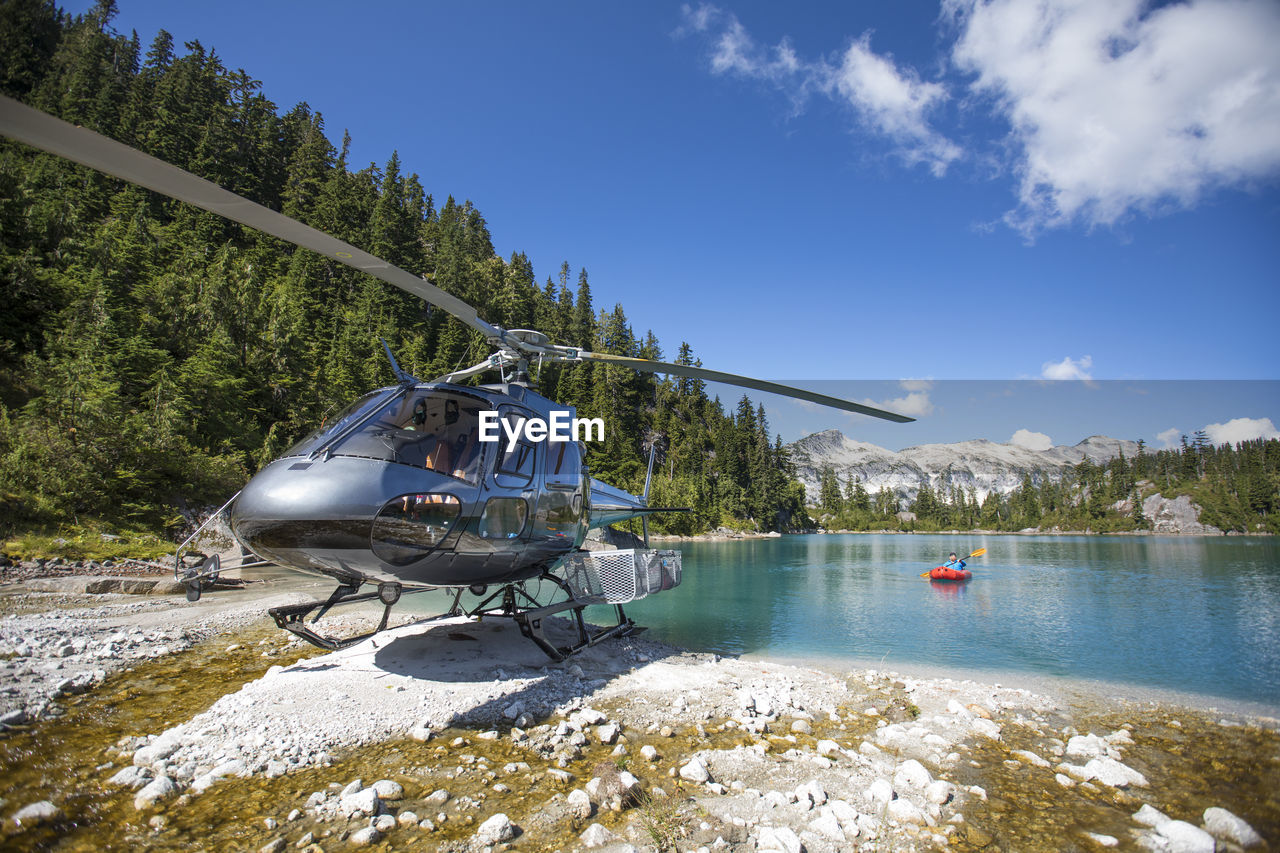 Active man paddling next to helicopter during adventure tour.