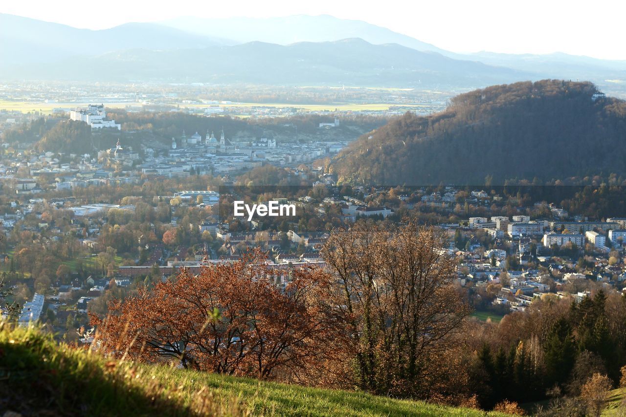 HIGH ANGLE VIEW OF TOWNSCAPE BY MOUNTAIN AGAINST SKY