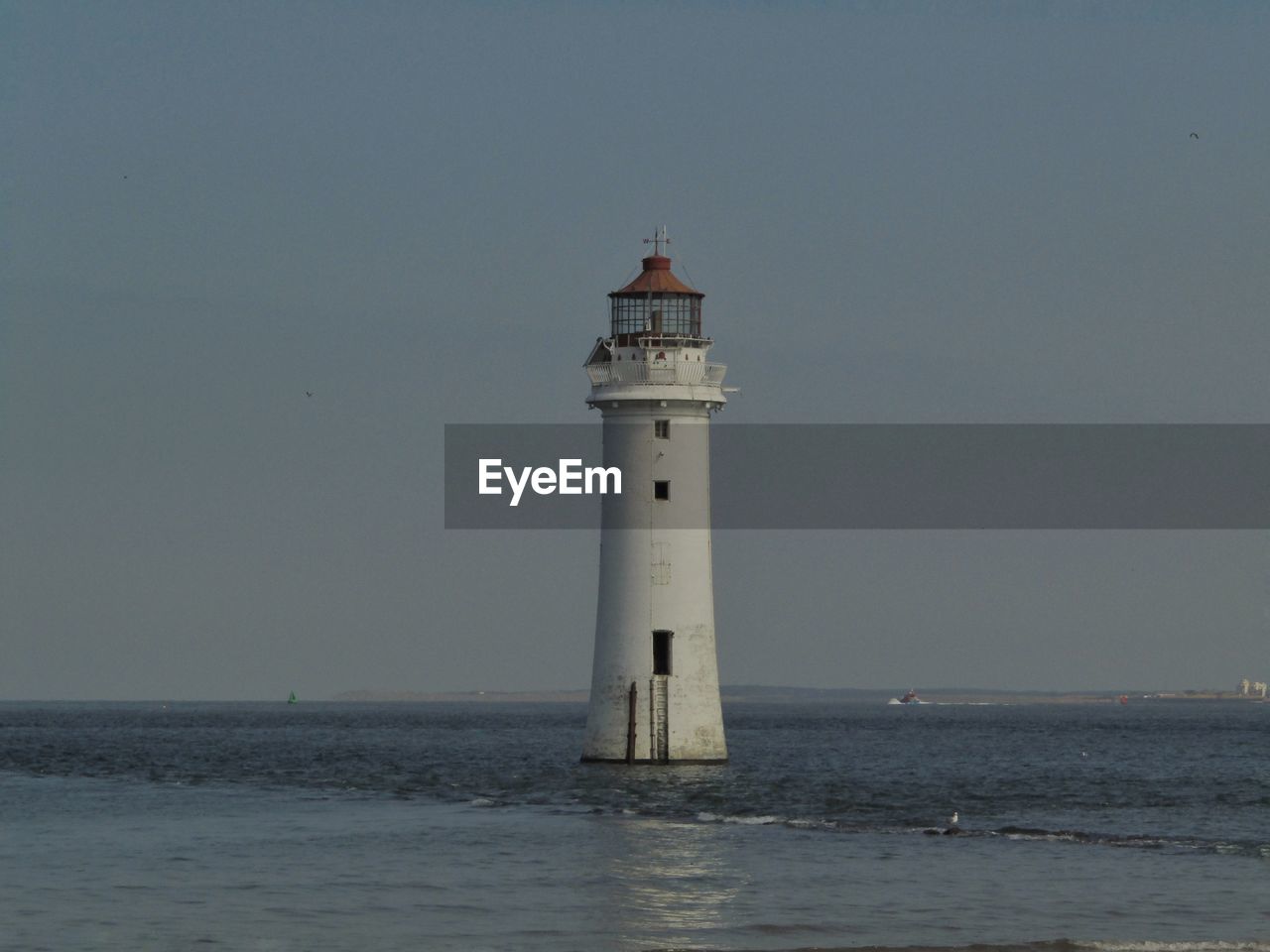 Lighthouse by sea against sky