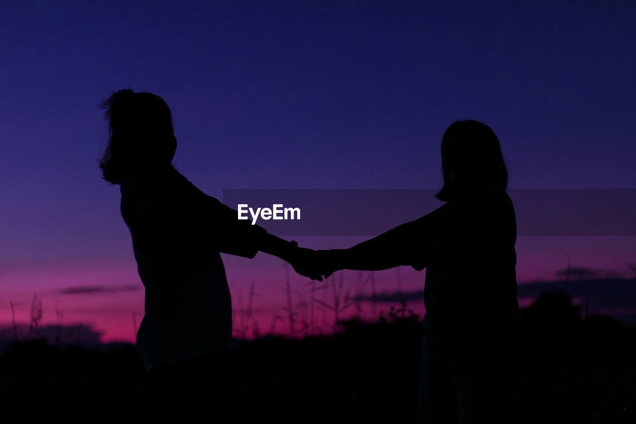 silhouette, sky, two people, sunset, emotion, love, darkness, women, togetherness, positive emotion, adult, nature, holding hands, dusk, bonding, men, backlighting, outdoors, child, night, standing, lifestyles, friendship, female, evening