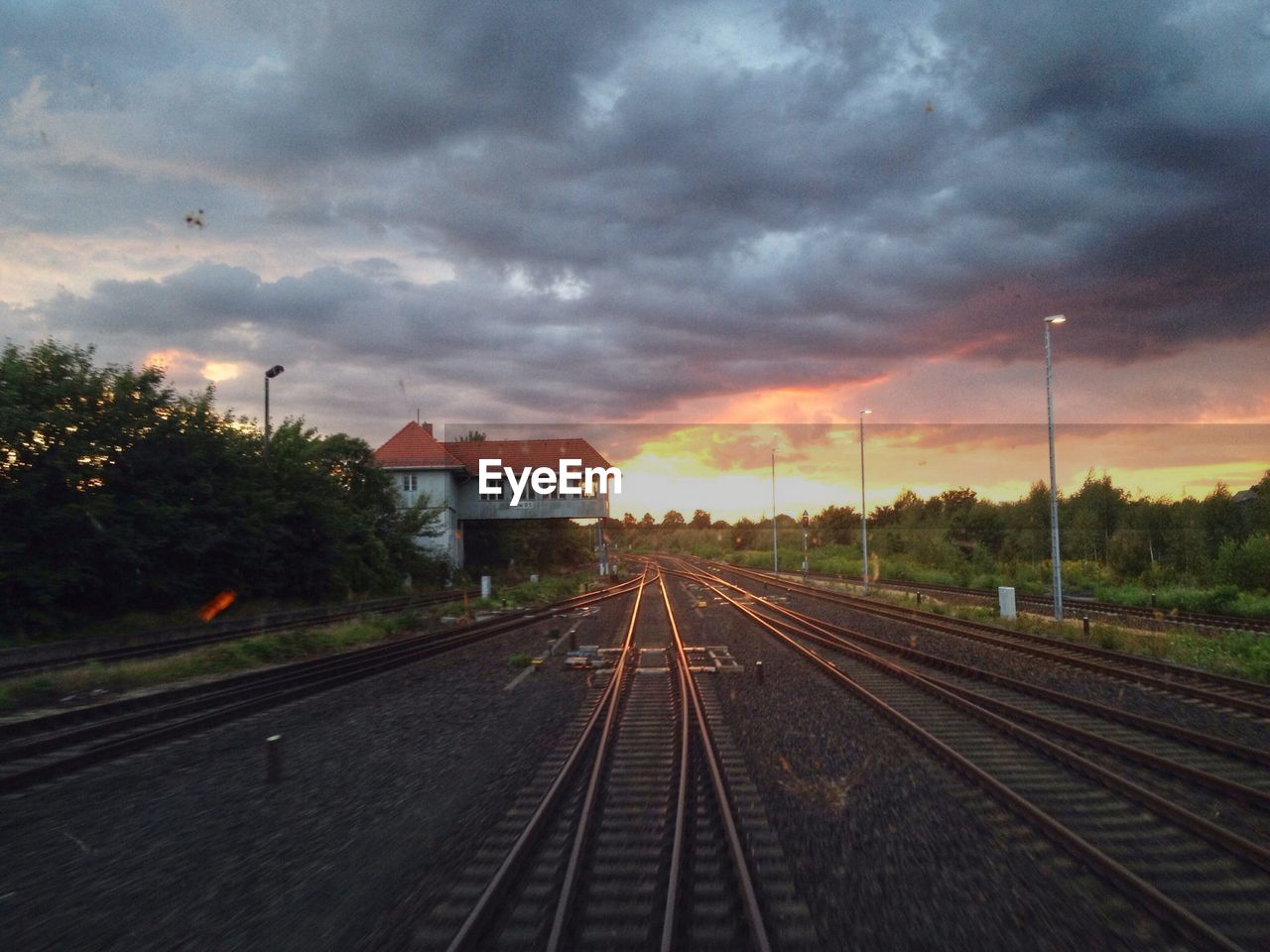 Railroad tracks against cloudy sky during sunset