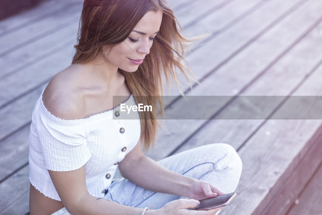 High angle view of woman using phone while sitting outdoors