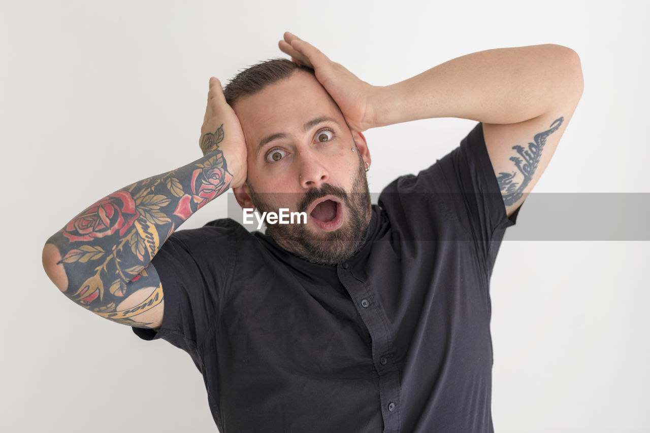 Portrait of shocked man standing against white background