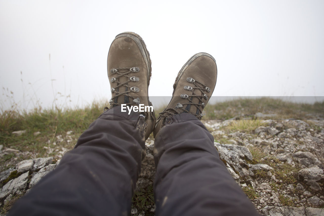 shoe, personal perspective, one person, low section, human leg, nature, leisure activity, footwear, lifestyles, limb, human limb, grass, day, relaxation, adult, winter, sky, casual clothing, men, outdoors, land, jeans, standing, human foot, plant, clothing, walking shoe, hiking, boot, trip, vacation, pants