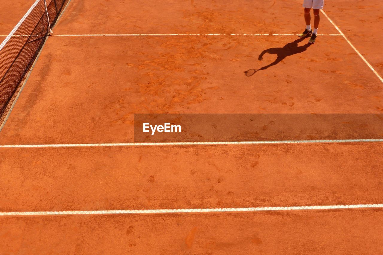 Low section of sportsman playing tennis on field