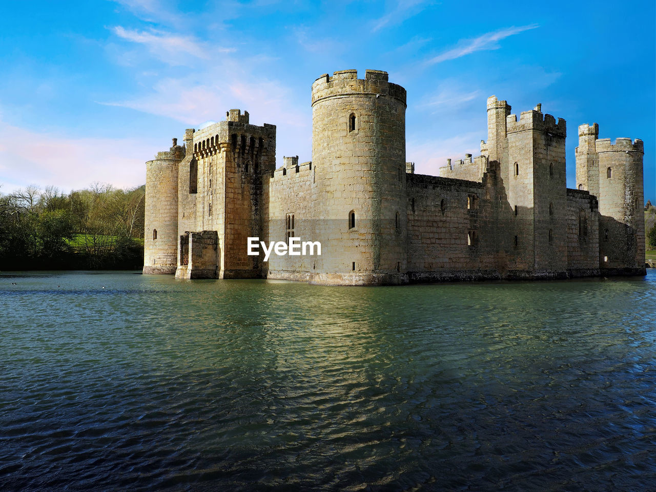 Castle by lake against sky