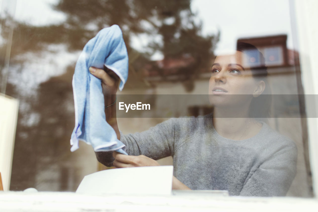 Woman cleaning glass of house window