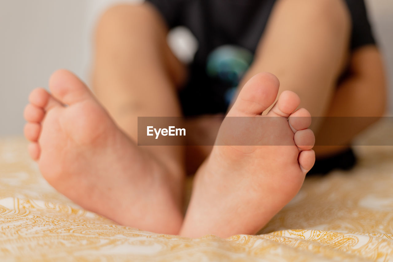 sole of foot, human leg, barefoot, human foot, toe, indoors, baby, toddler, child, one person, close-up, limb, relaxation, childhood, lying down, finger, adult, bed, selective focus, domestic room, low section, women, furniture, person, sitting, hand, bedroom, lifestyles, human limb, nail, domestic life, female, heel