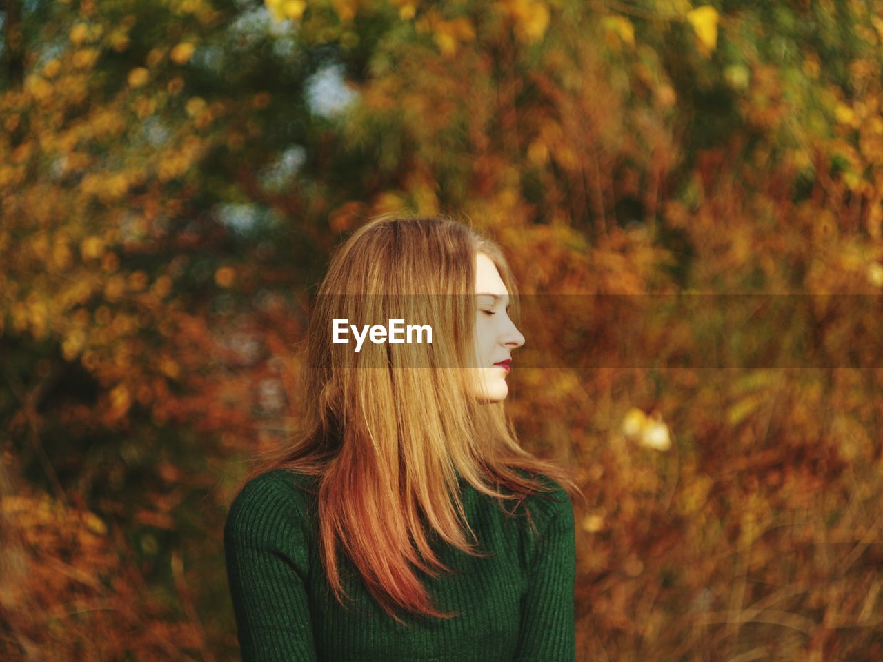 Young woman with eyes closed in park during autumn