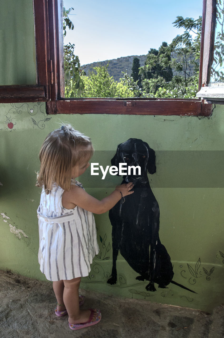 GIRL WITH DOG STANDING BY TREE