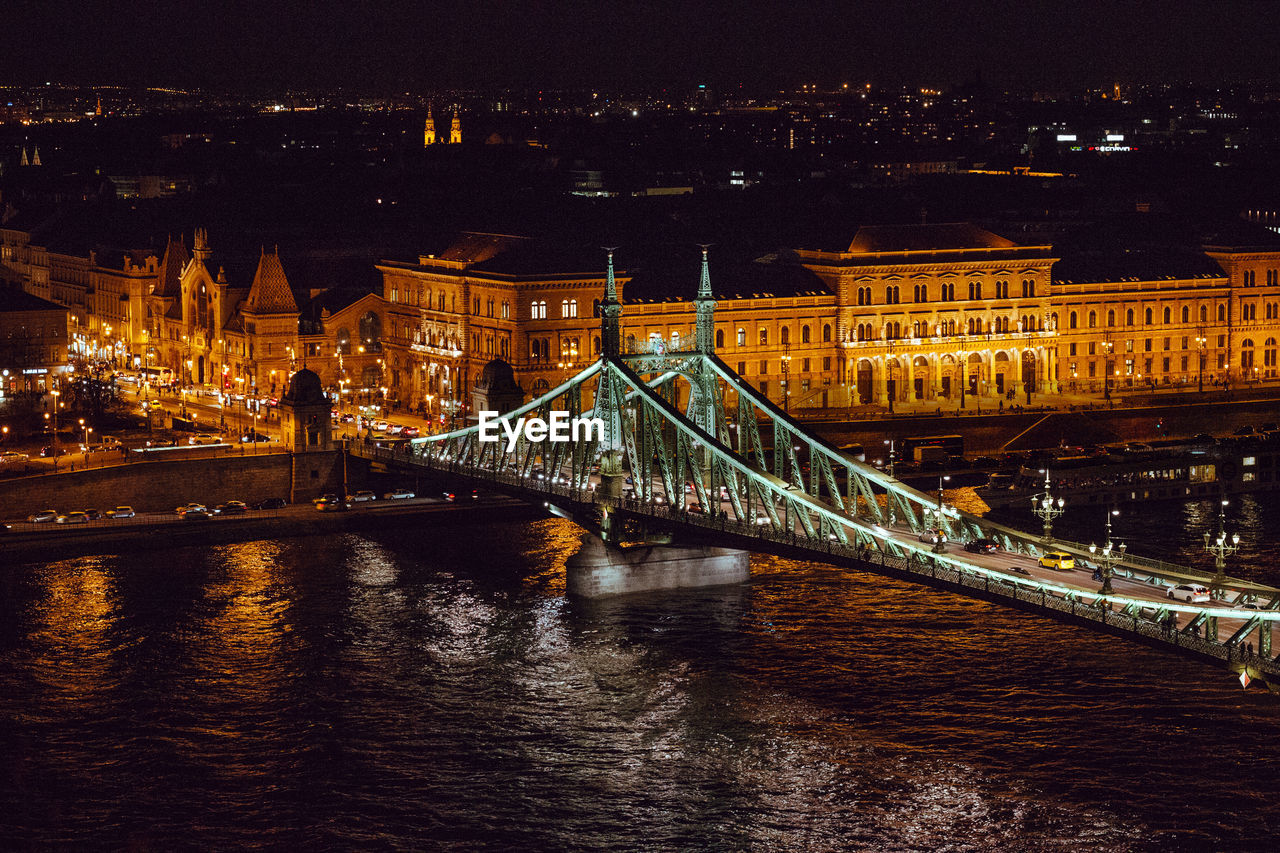 Illuminated bridge over river at night