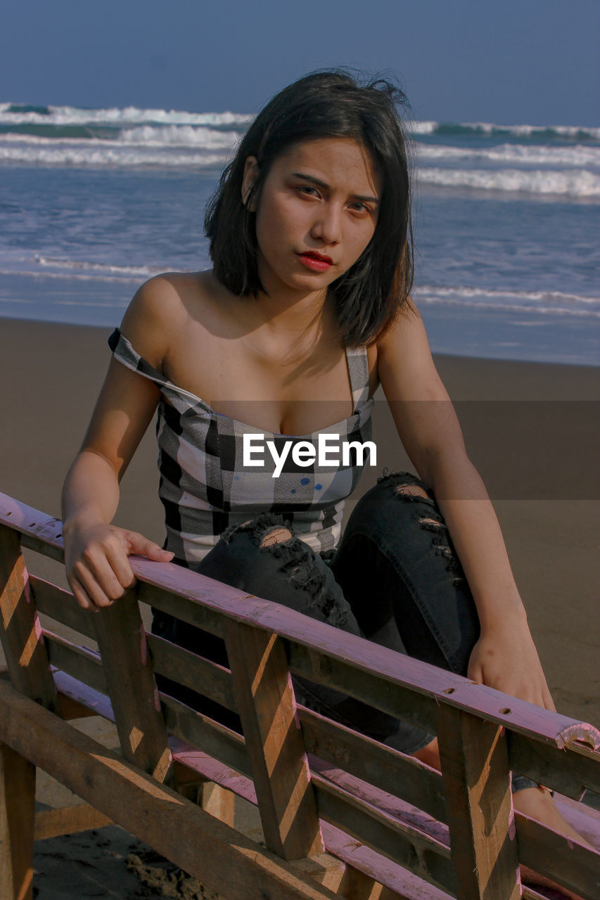 Portrait of young woman sitting on beach at beach during sunny day