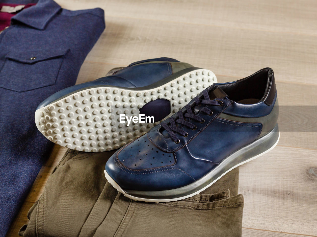 Men's sneakers lie on jeans of a swamp shade, close-up, side view