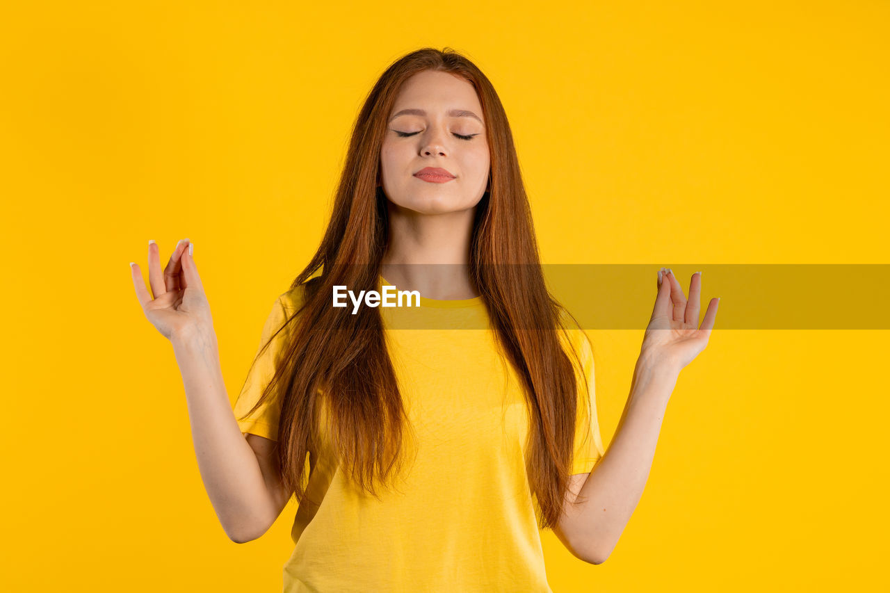 yellow, long hair, yellow background, one person, colored background, hairstyle, studio shot, young adult, women, portrait, adult, waist up, indoors, front view, brown hair, smiling, happiness, emotion, fashion, copy space, standing, casual clothing, eyes closed, human face, arm, finger, hand, photo shoot, looking at camera, child, teenager, human hair, clothing, blond hair, person