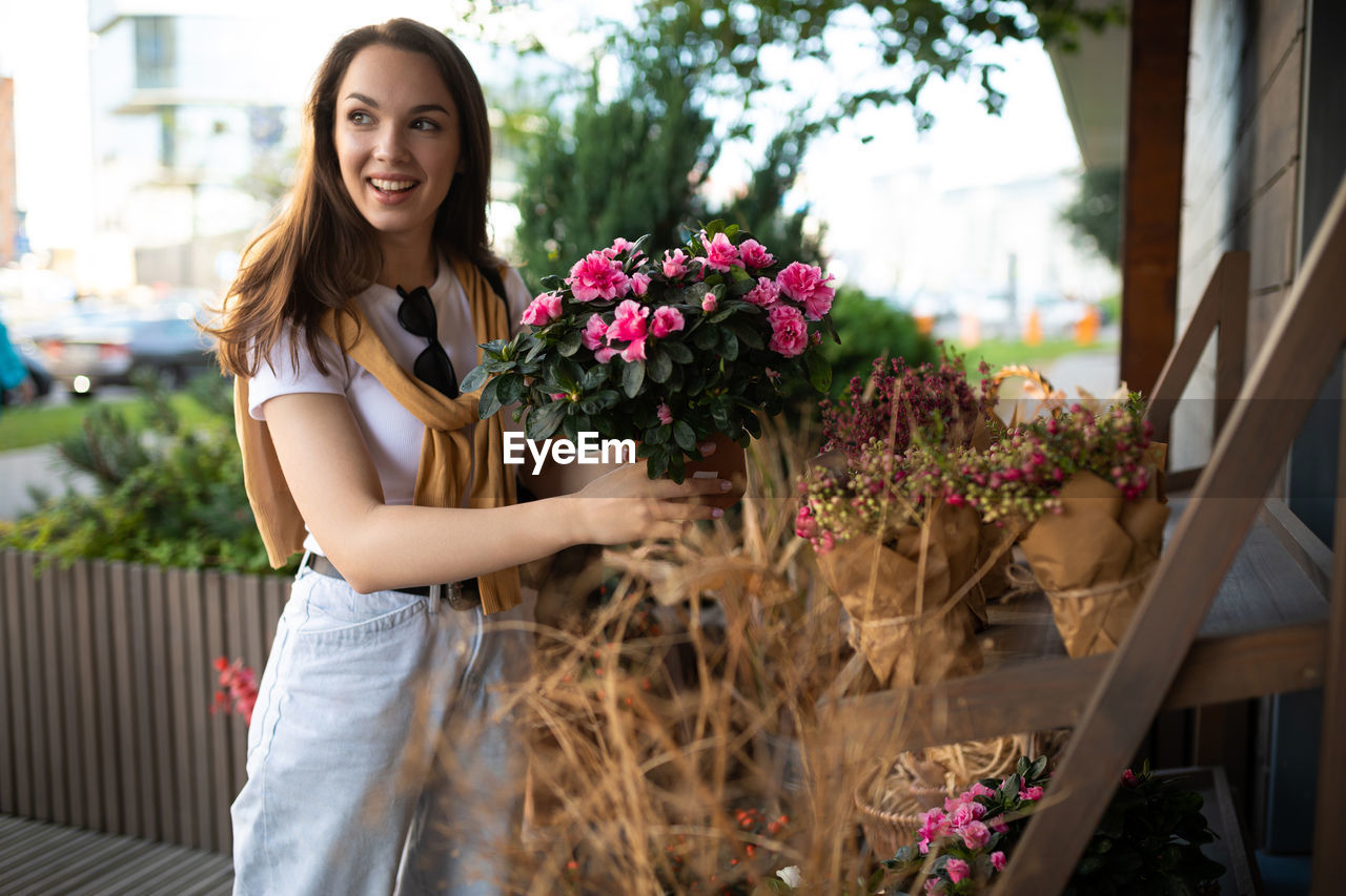 portrait of smiling young woman standing by plants