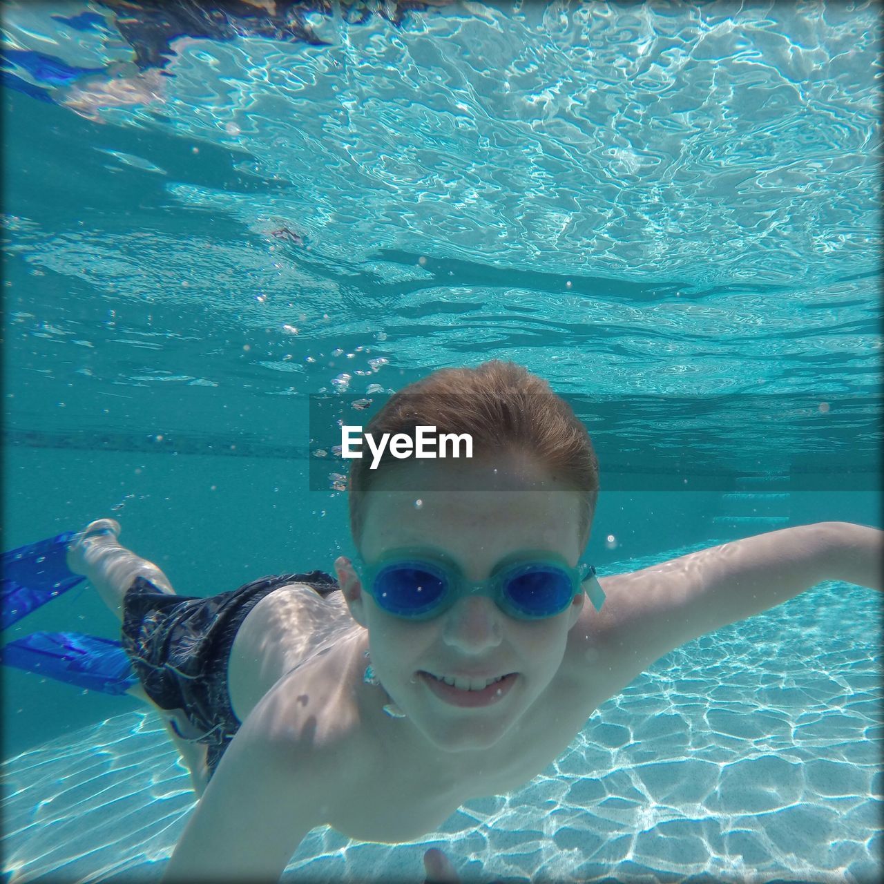 Shirtless boy in goggles swimming in pool