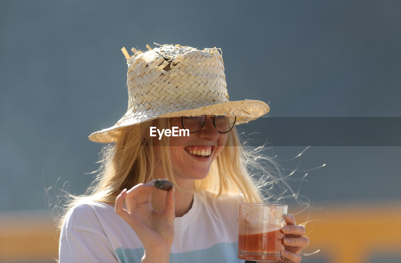 PORTRAIT OF A YOUNG WOMAN DRINKING FROM GLASS