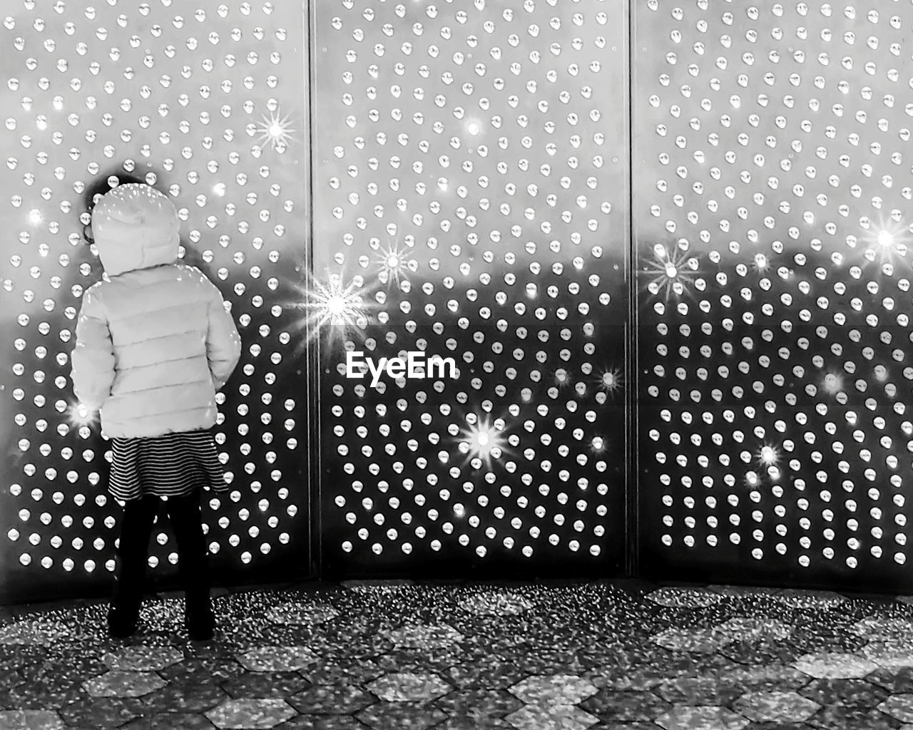 REAR VIEW OF MAN STANDING ON ILLUMINATED WALL