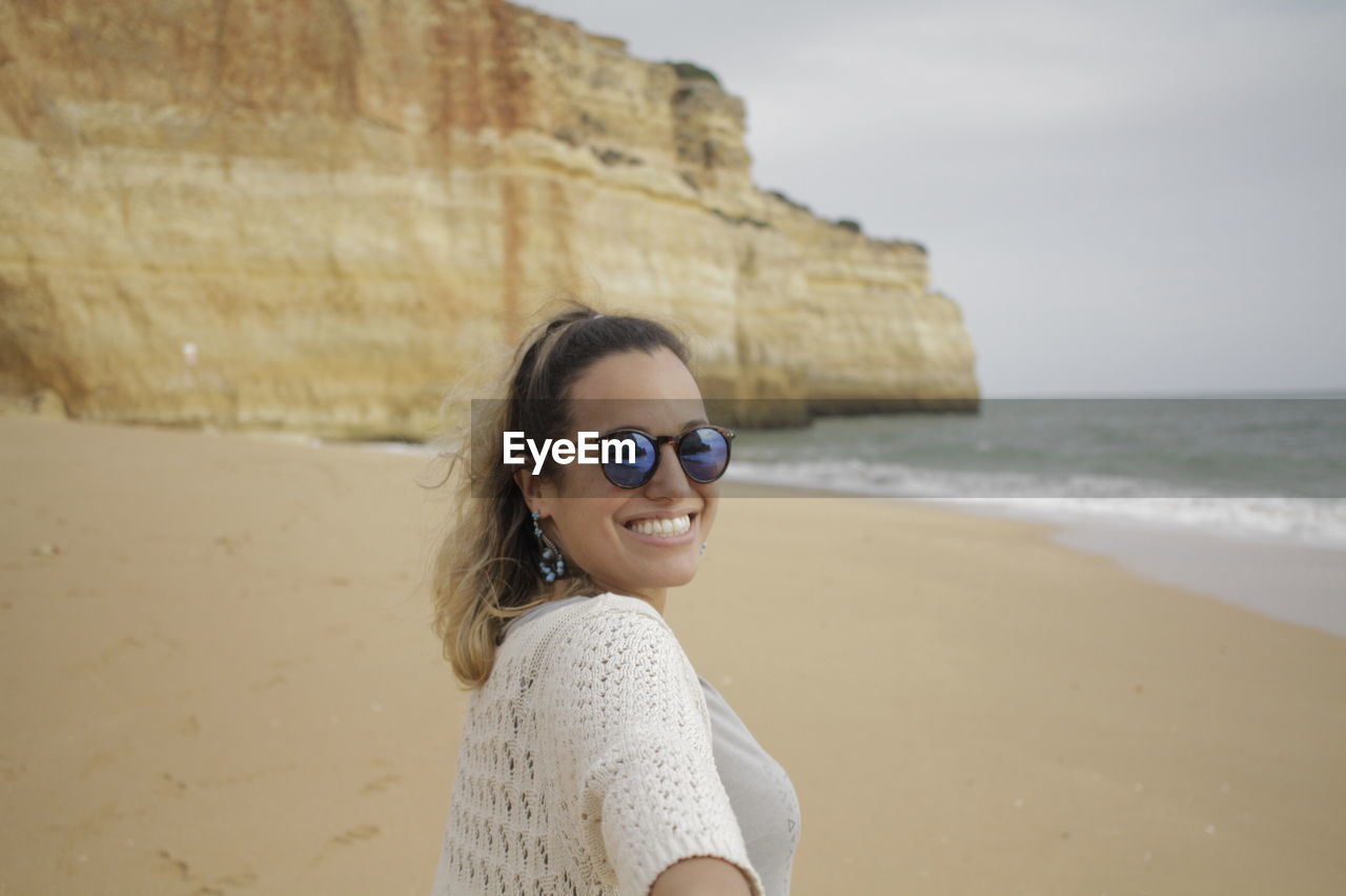 Portrait of smiling woman standing at beach