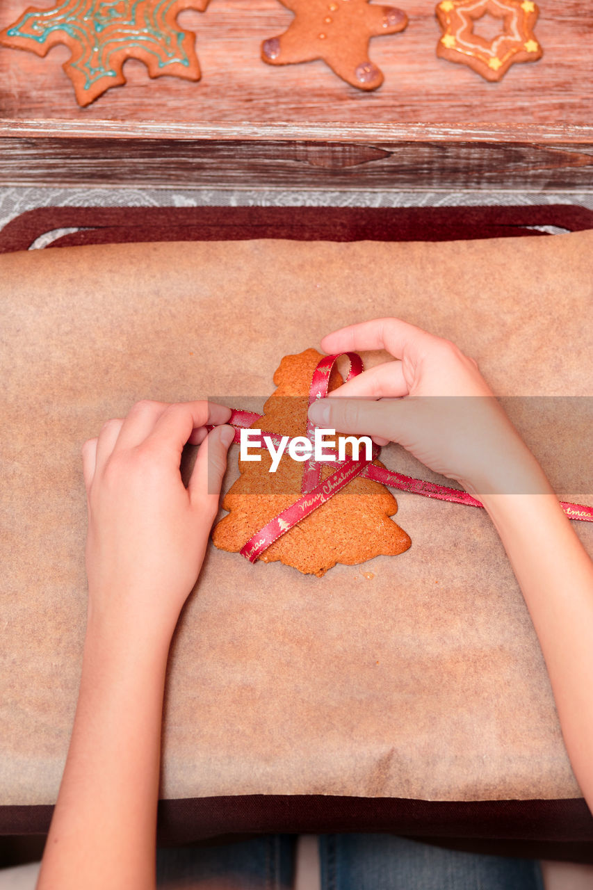 Cropped hands of woman preparing gingerbread cookies on table